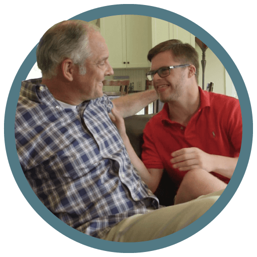 A father and his son sit on a couch talking